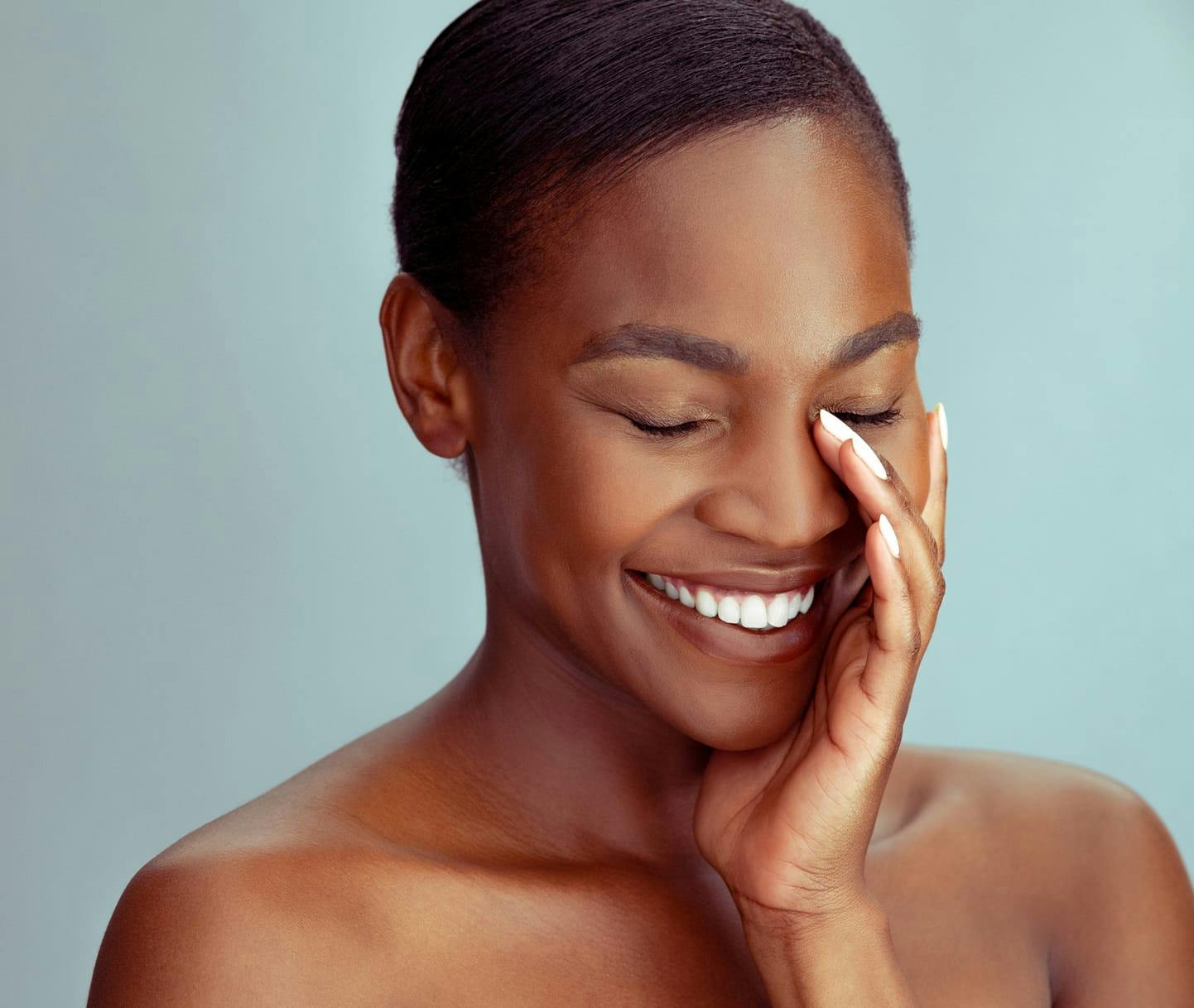 woman smiling and touching her face
