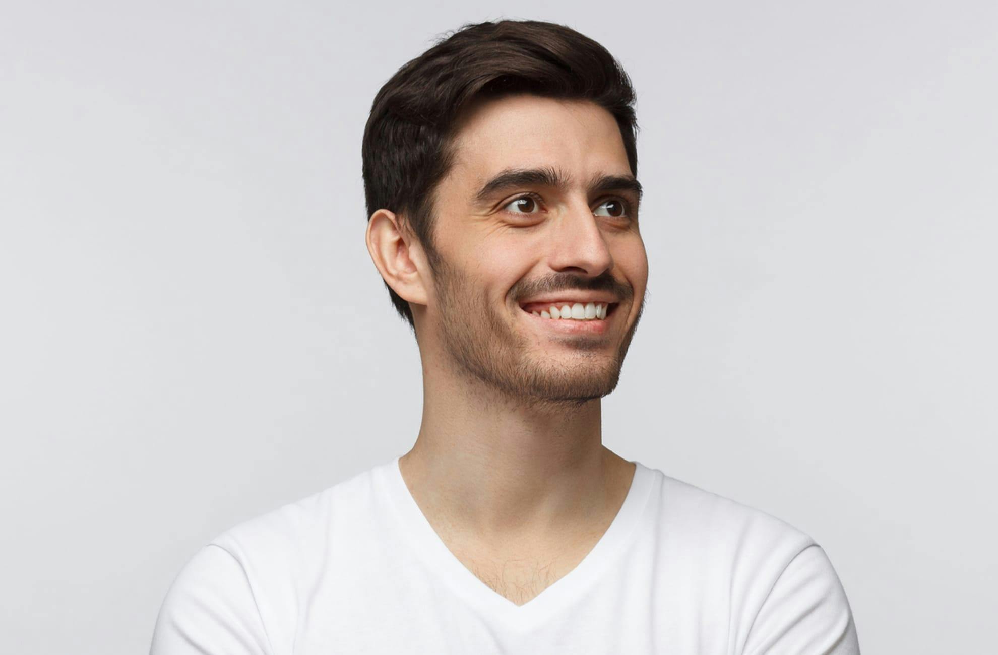 black haired man smiling in a white tshirt