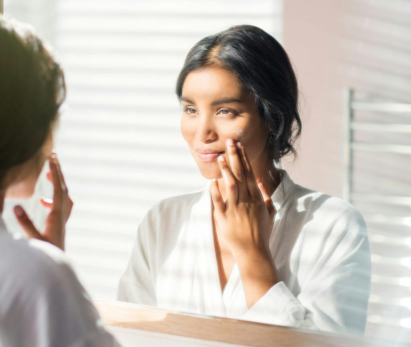 Woman looking in the mirror touching face