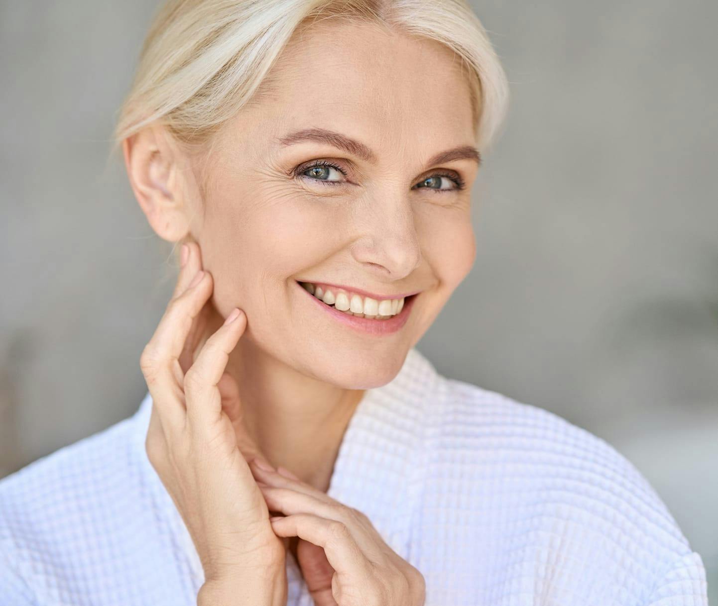 woman smiling and touching her lower face