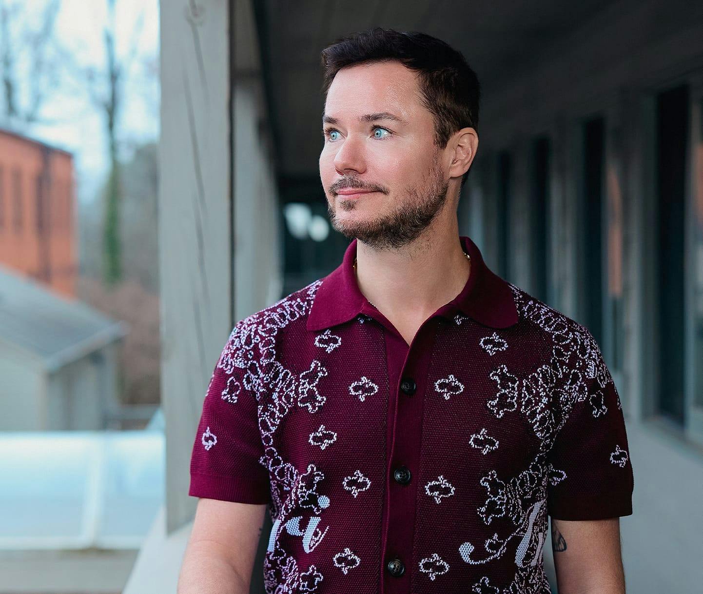 man walking outside wearing maroon patterned shirt