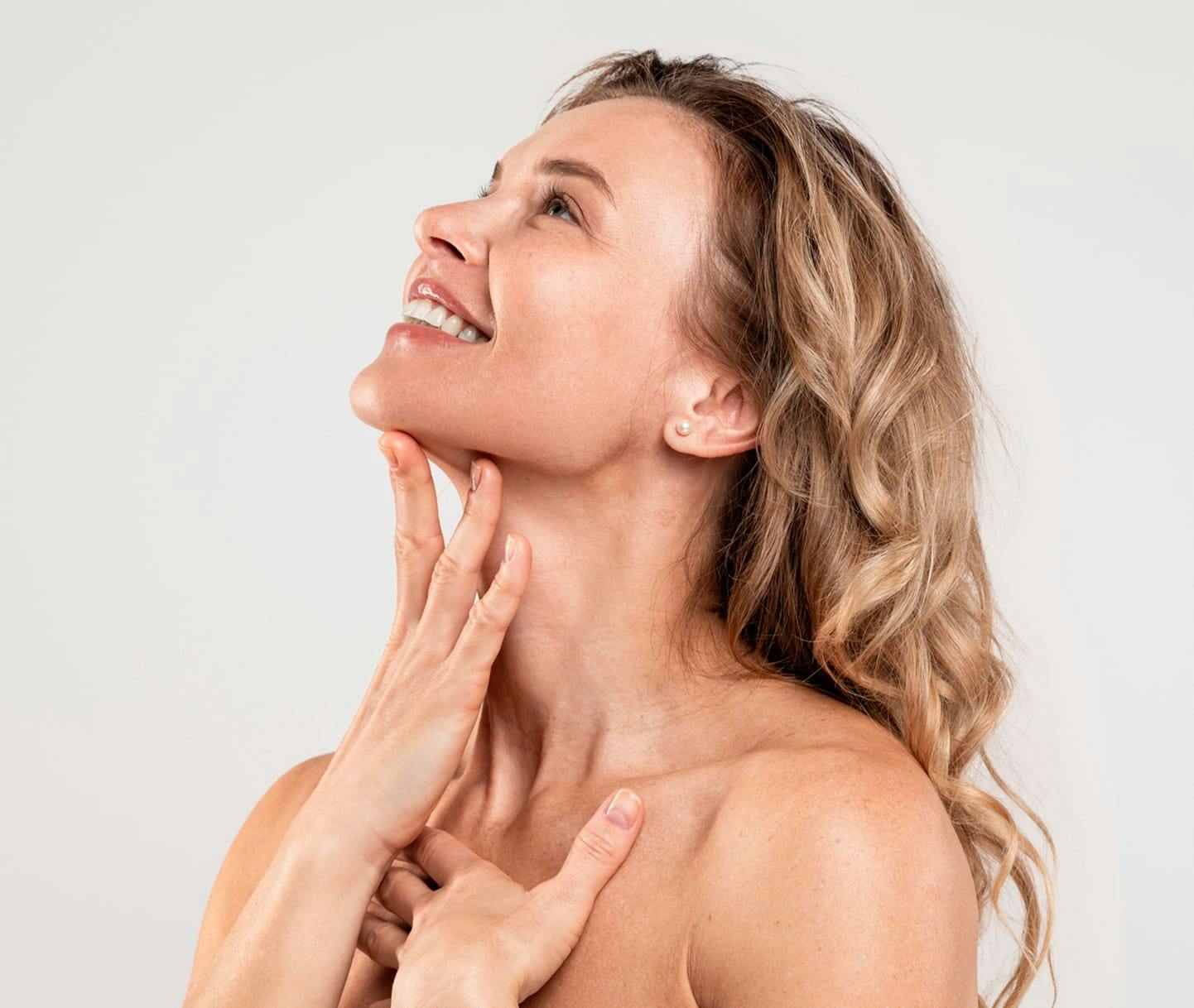 Woman smiling and touching neck while looking up
