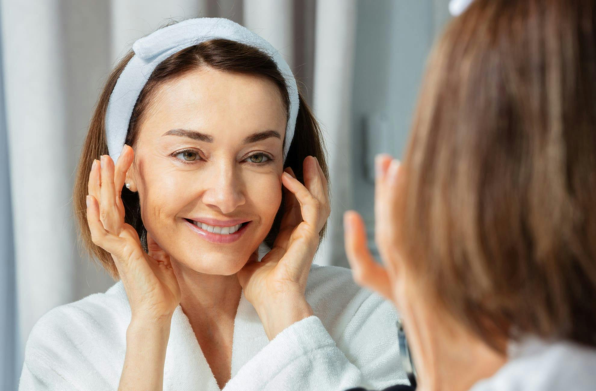 Woman touching face and smiling in the mirror