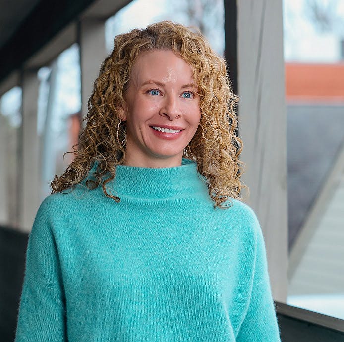 woman with blonde curly hair wearing a blue sweater
