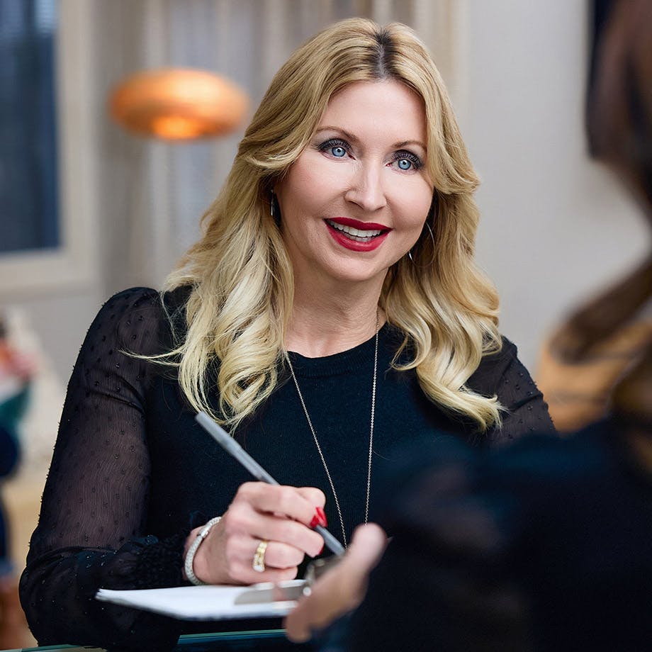 woman with blonde hair signing paperwork