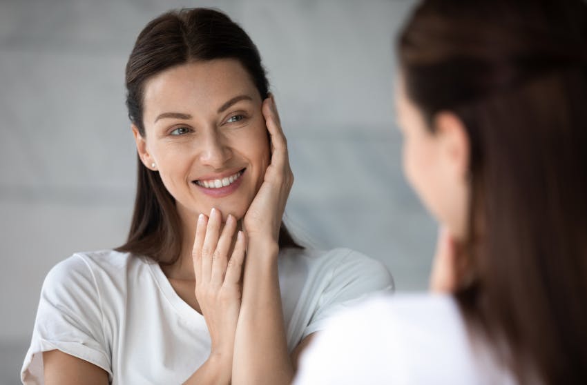 woman looking in a mirror while smiling