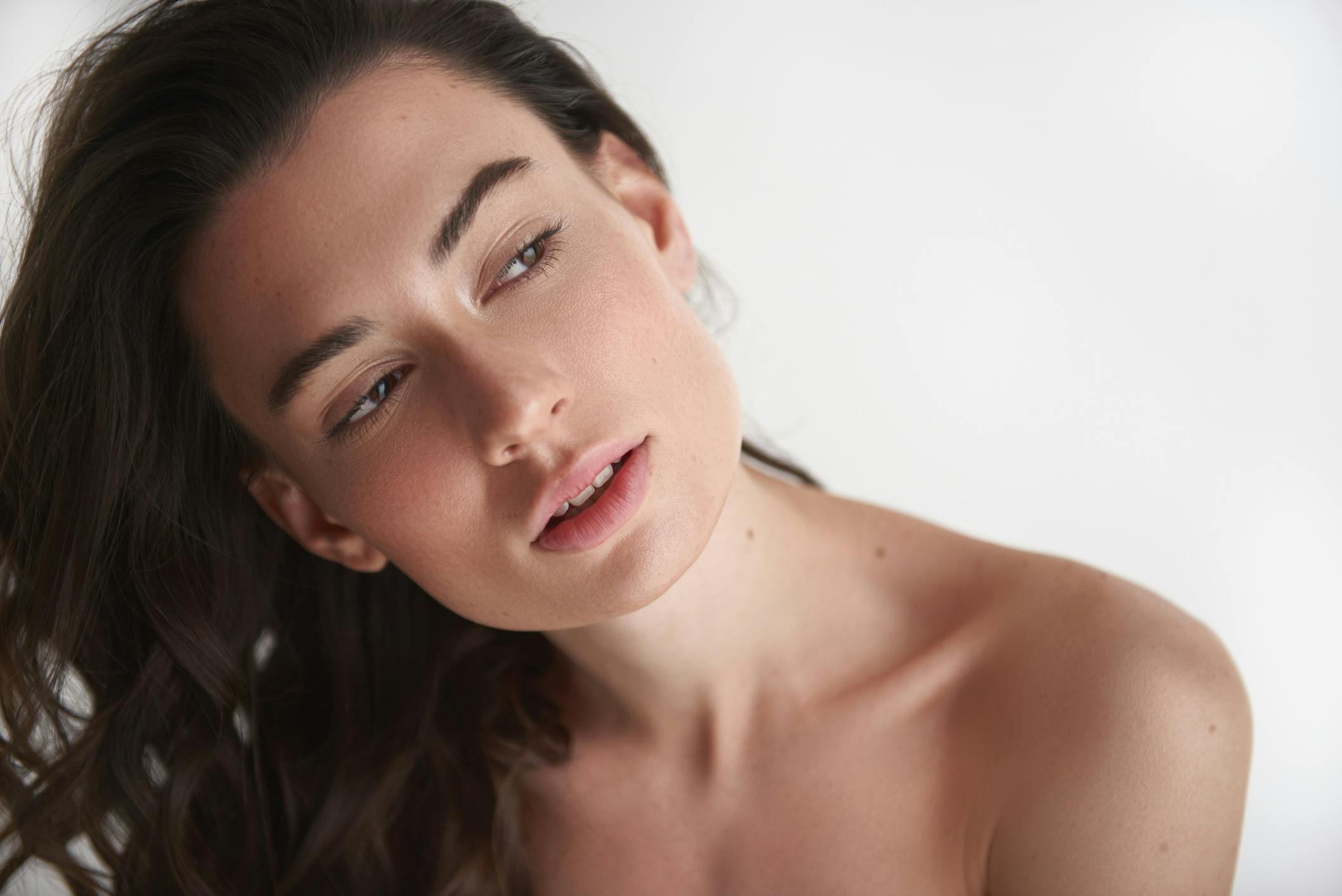 Woman with beautiful skin in studio shoot looks away from camera.
