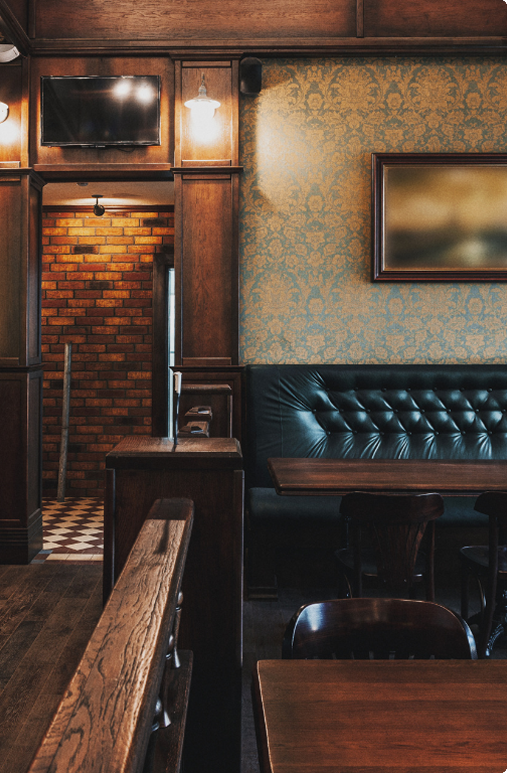 A dark wood bar with leather green seating
