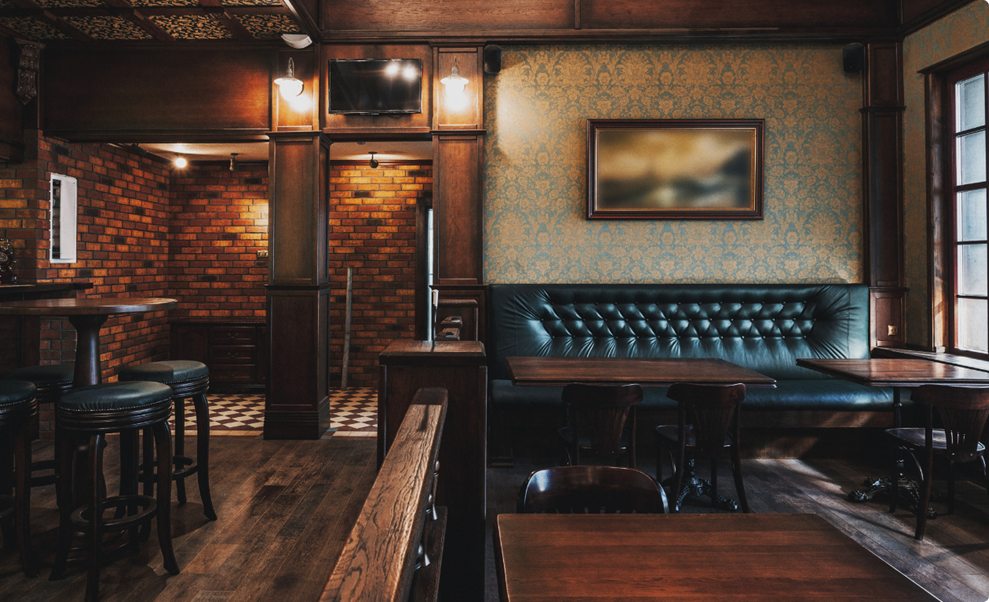 A dark wood bar with green leather seating