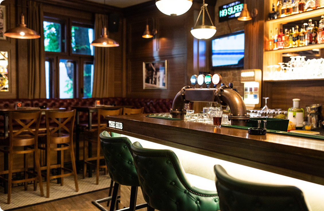 Dark cosy bar with green leather seats and wooden accents