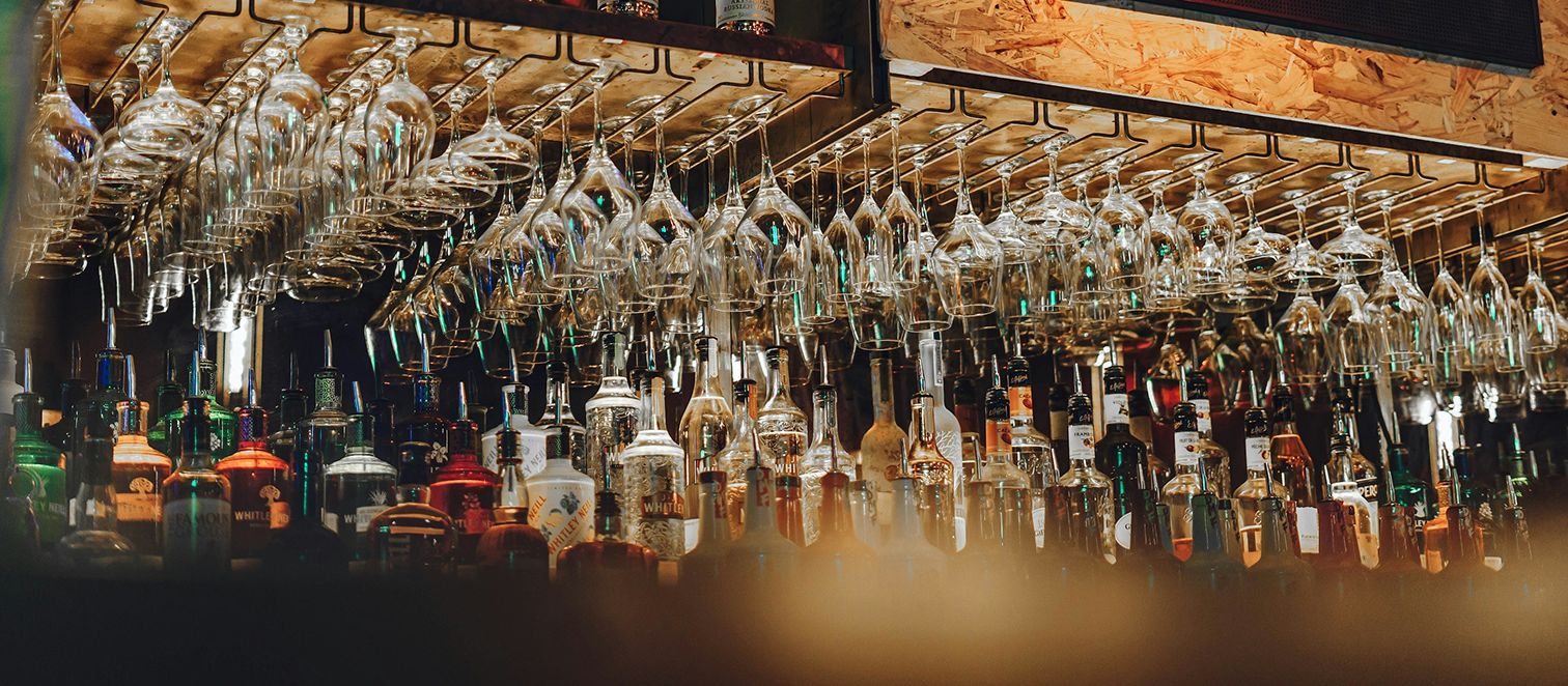 Wine glasses hanging upside down in a bar over liquor bottles