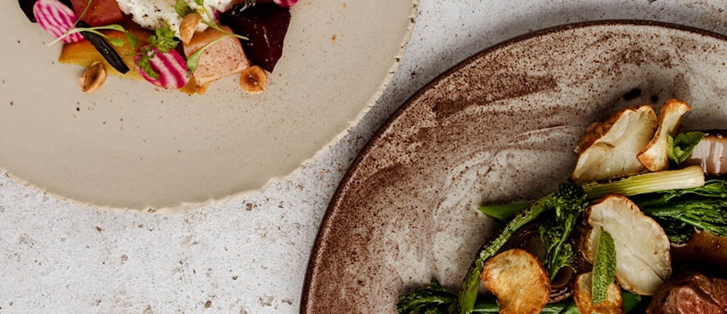 Two plates of gourmet food on stone plateware