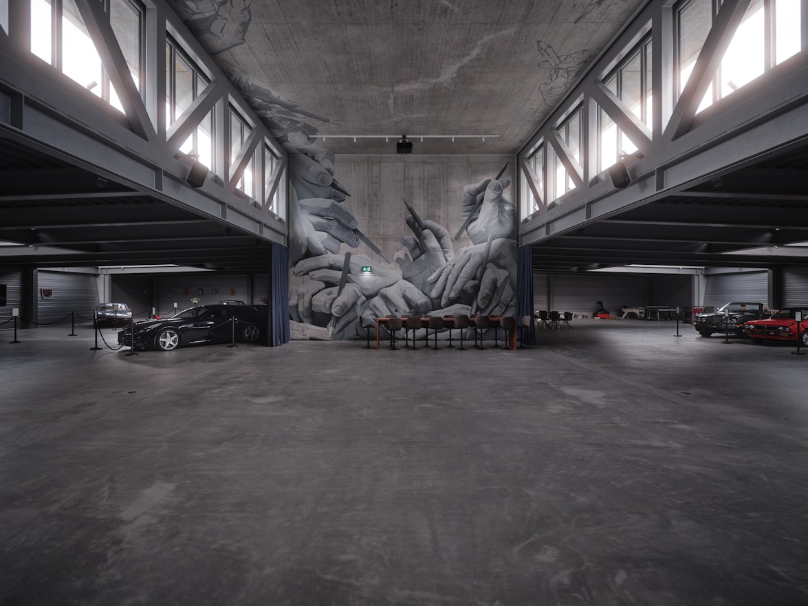 Eine geräumige Industriegarage mit geparkten Autos und einem Wandgemälde mit ineinandergreifenden Händen unter hohen Decken und großen Fenstern.