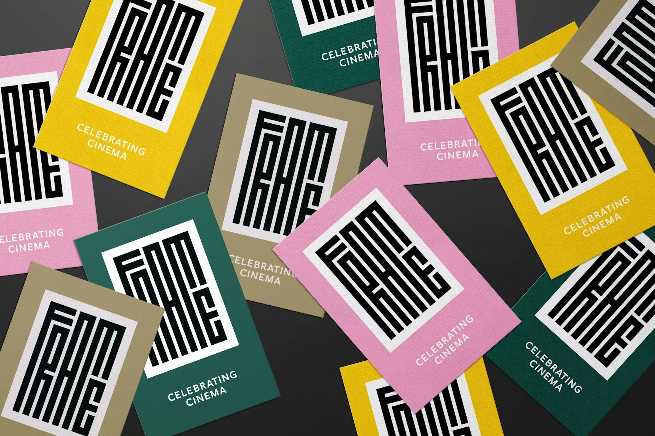 Mehrere Karten in Pink, Grün und Gold zeigen ein auffälliges, schwarz-weißes geometrisches „FAME“-Logo mit dem Untertitel „CELEBRATING CINEMA“, das über eine dunkle Oberfläche verstreut ist.