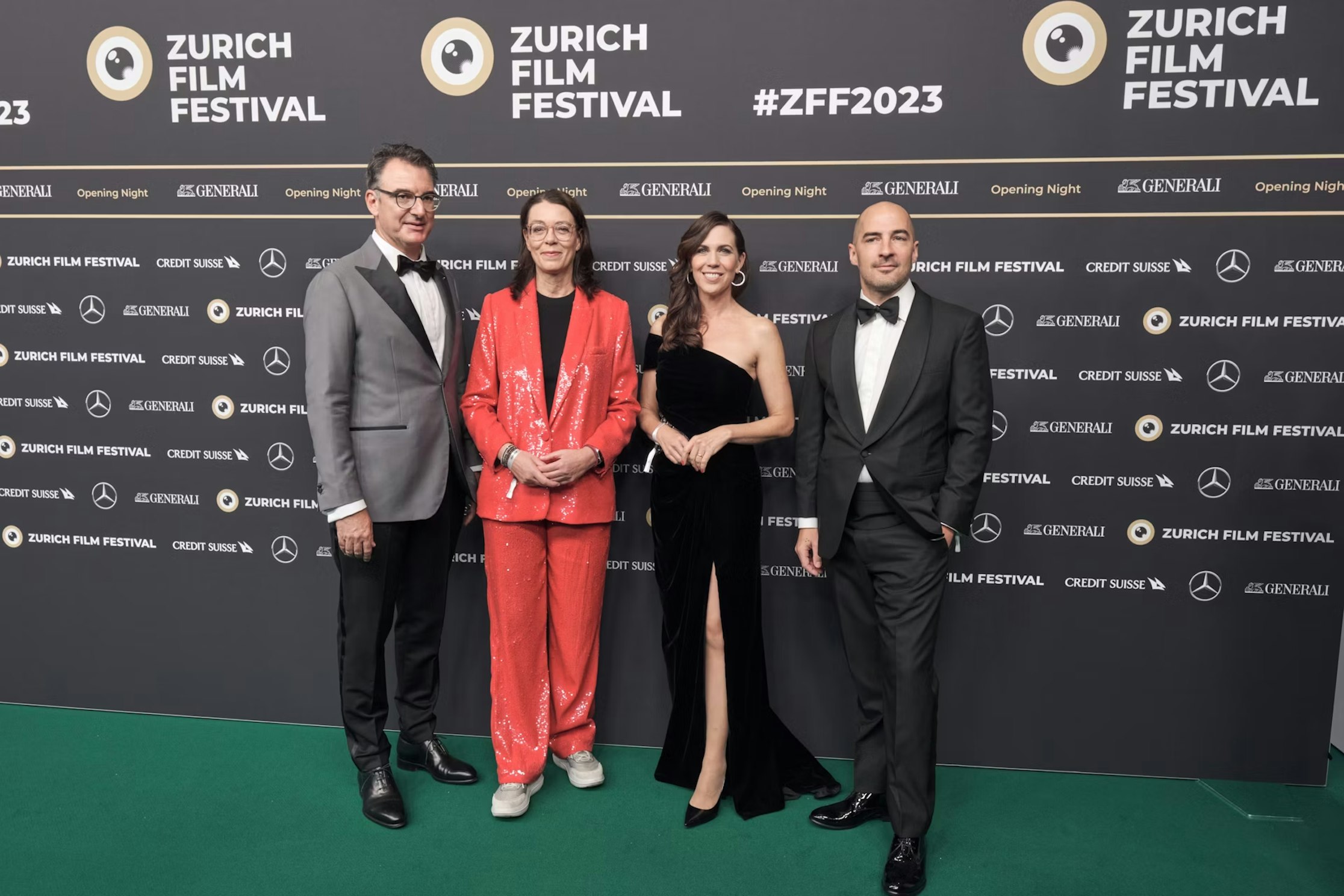 Vier Personen in Abendgarderobe posieren auf dem grünen Teppich des Zurich Film Festival 2023 vor einer Markenkulisse mit Logos und dem Namen der Veranstaltung.