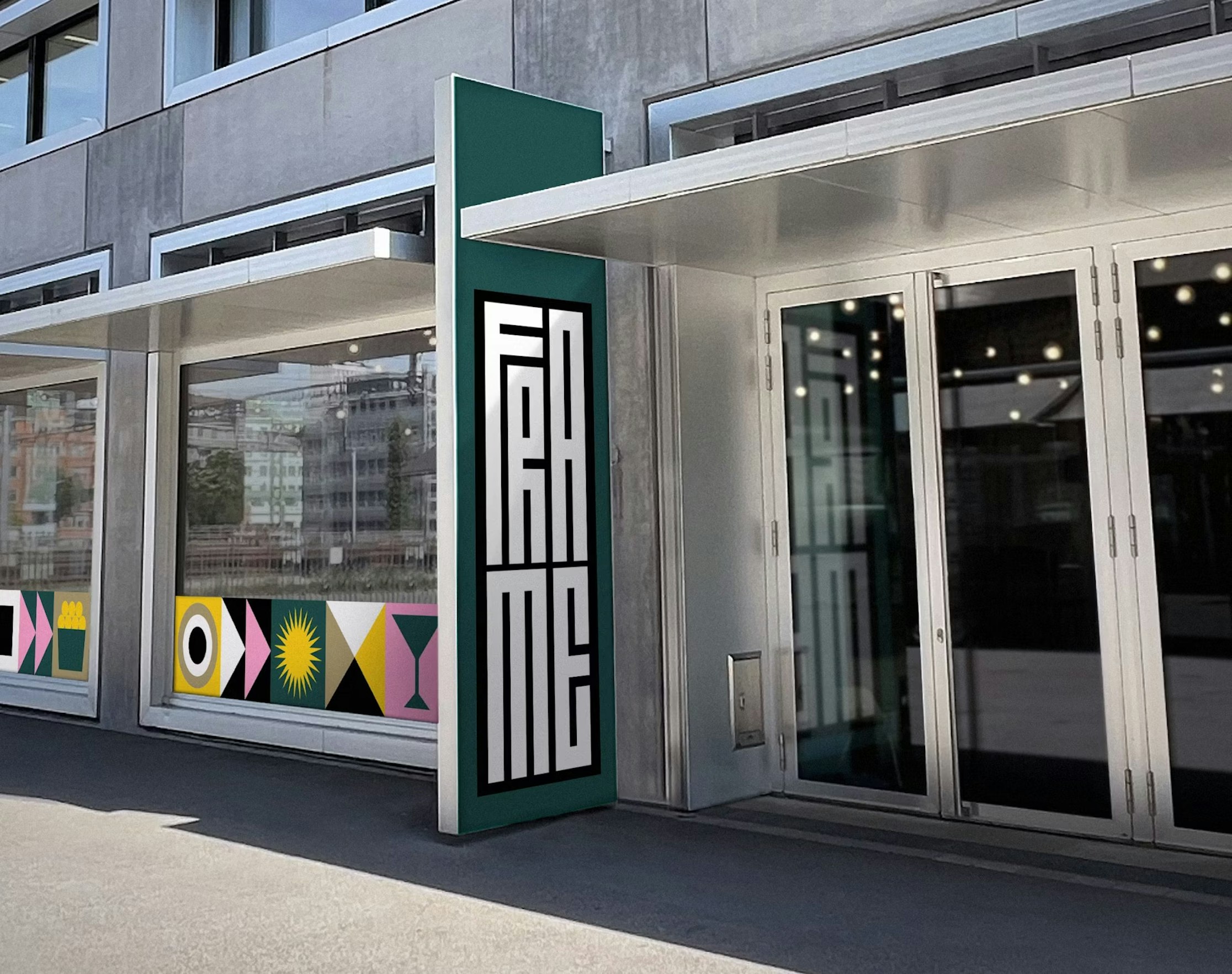 Eine moderne Gebäudefassade mit Glastüren und einem vertikalen Schild mit der Aufschrift „FRAME“ in fetten, stilisierten Buchstaben. Das Fenster zeigt farbenfrohe geometrische Formen und Muster.