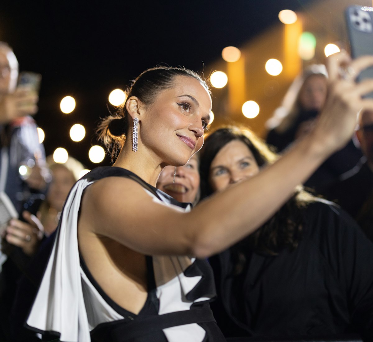 Frau mit Handy wo mit Gäste ein Selfie macht