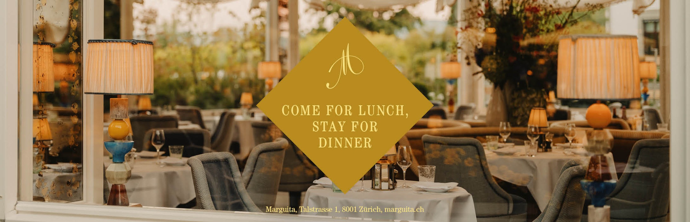 Elegantes Restaurantinterieur durch ein Fenster gesehen, mit gedeckten Tischen und warmer Beleuchtung. Auf einem goldenen rautenförmigen Schild steht: "Kommen Sie zum Mittagessen, bleiben Sie zum Abendessen". Details zum Restaurant finden Sie unten.