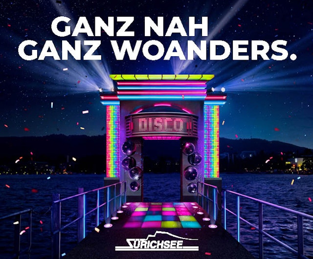 Ein bunter, beleuchteter Disco-Eingang auf einem Pier über einem See bei Nacht mit Konfetti in der Luft. Der Text lautet GANZ NAH GANZ WOANDERS. und ZÜRICHSEE am unteren Rand.