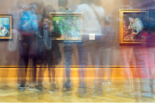 Long exposure color photo of people walking through a museum hall