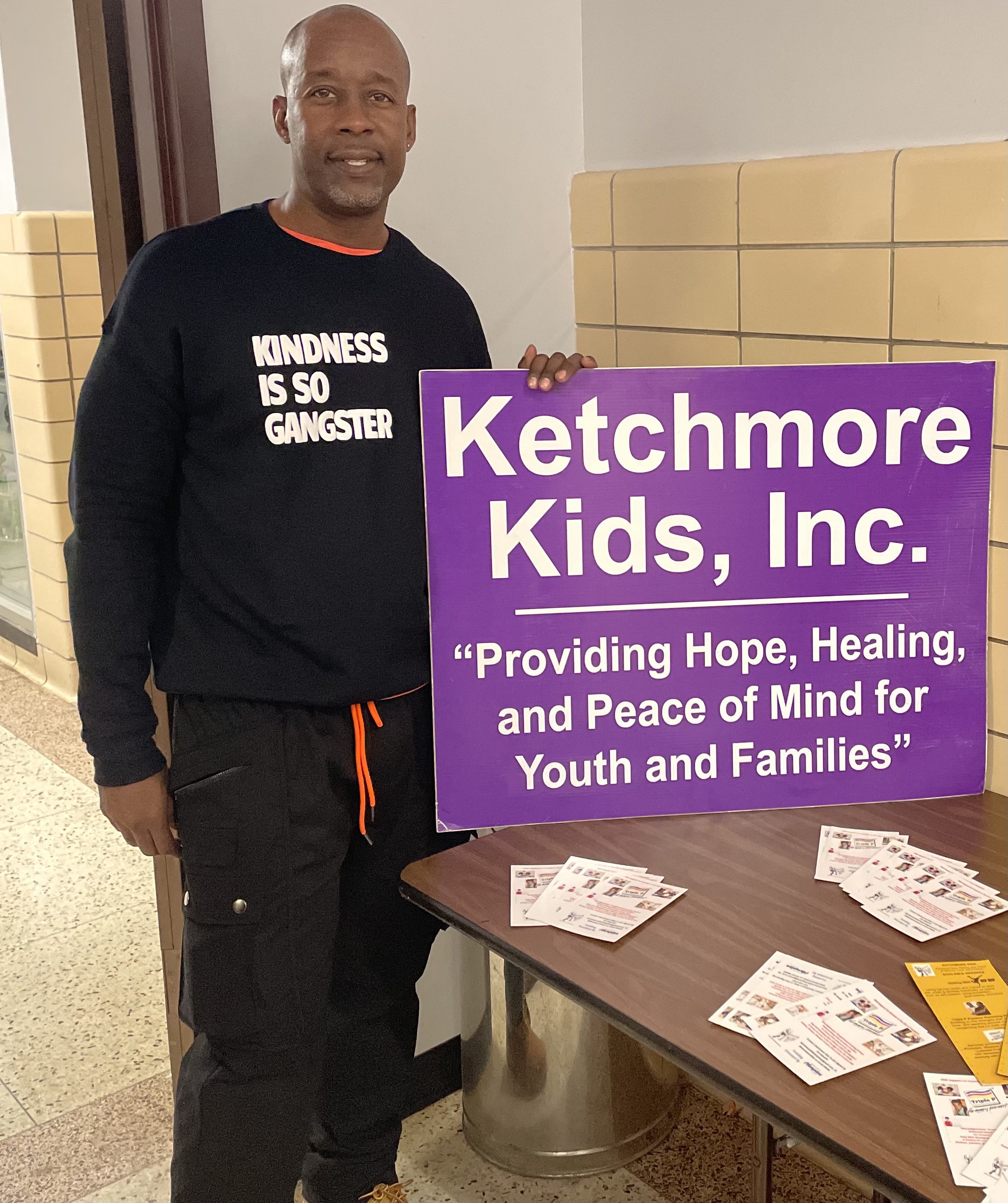 Photograph of Troy Ketchmore wearing a shirt that reads 'Kindness is so gangster'