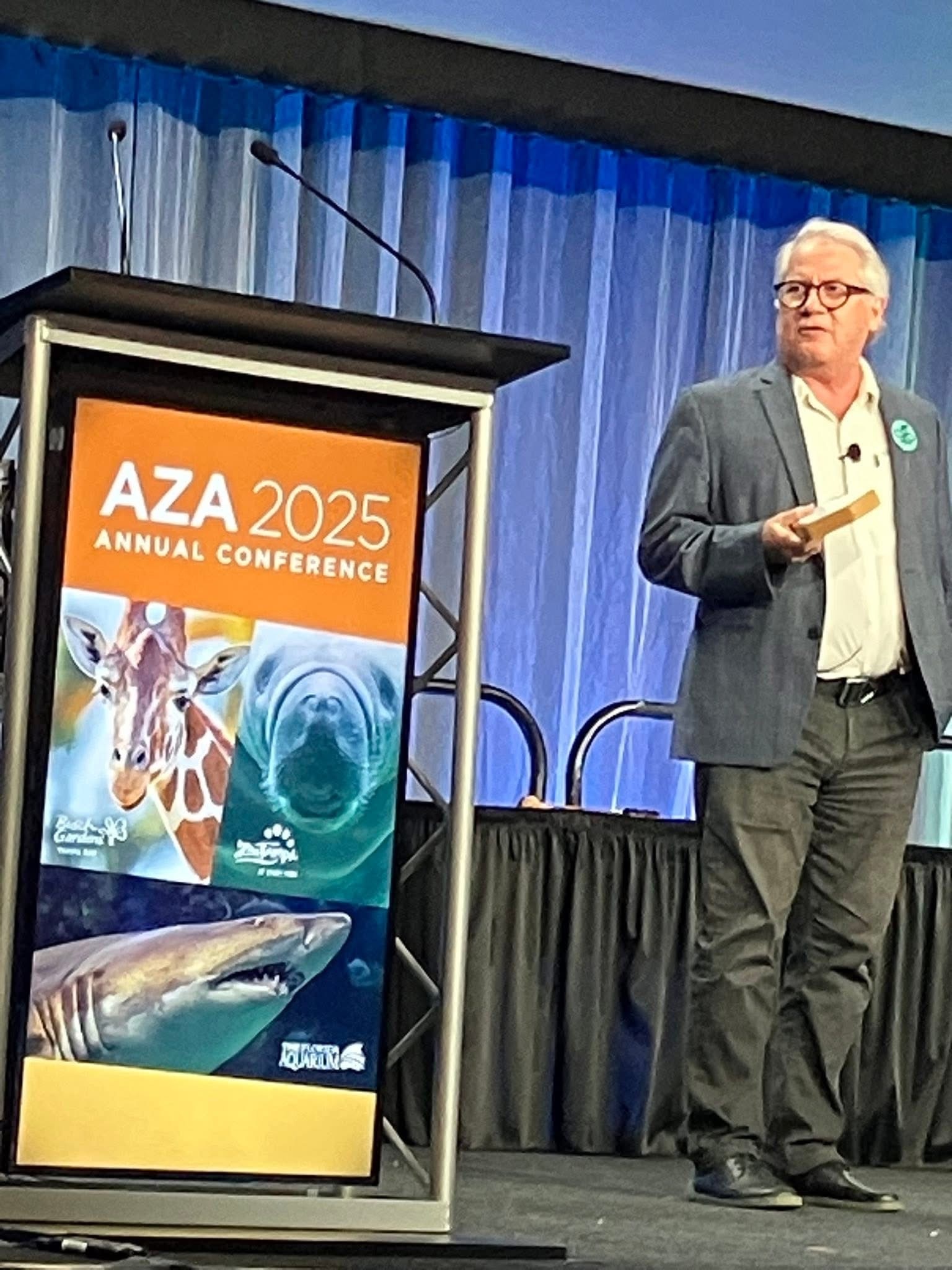 Speaker on stage beside AZA 2025 podium sign