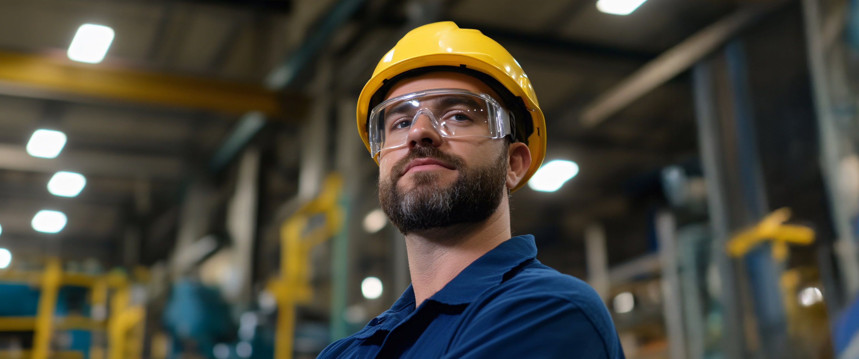 Factory worker wearing helmet and safety glasses.