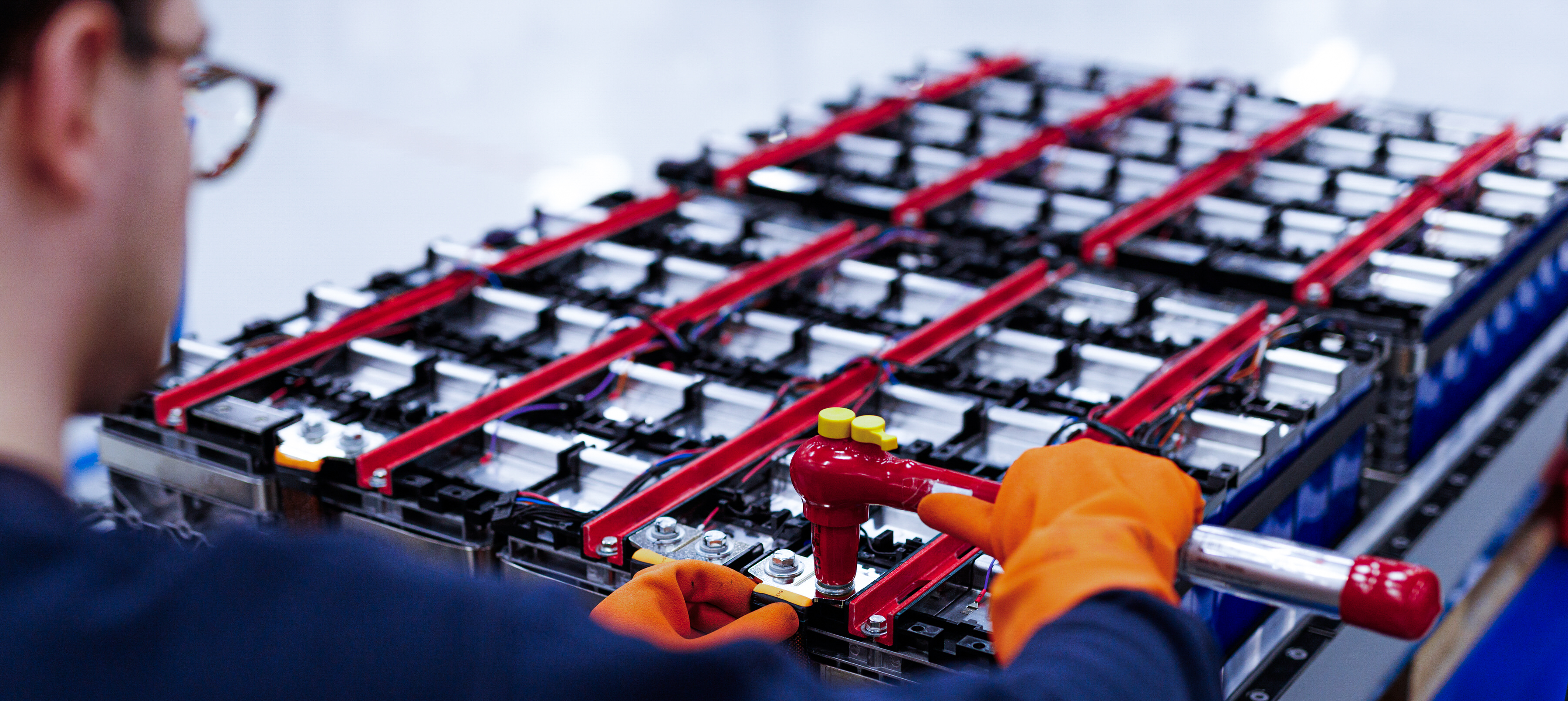 Technician assembling battery modules with tools.