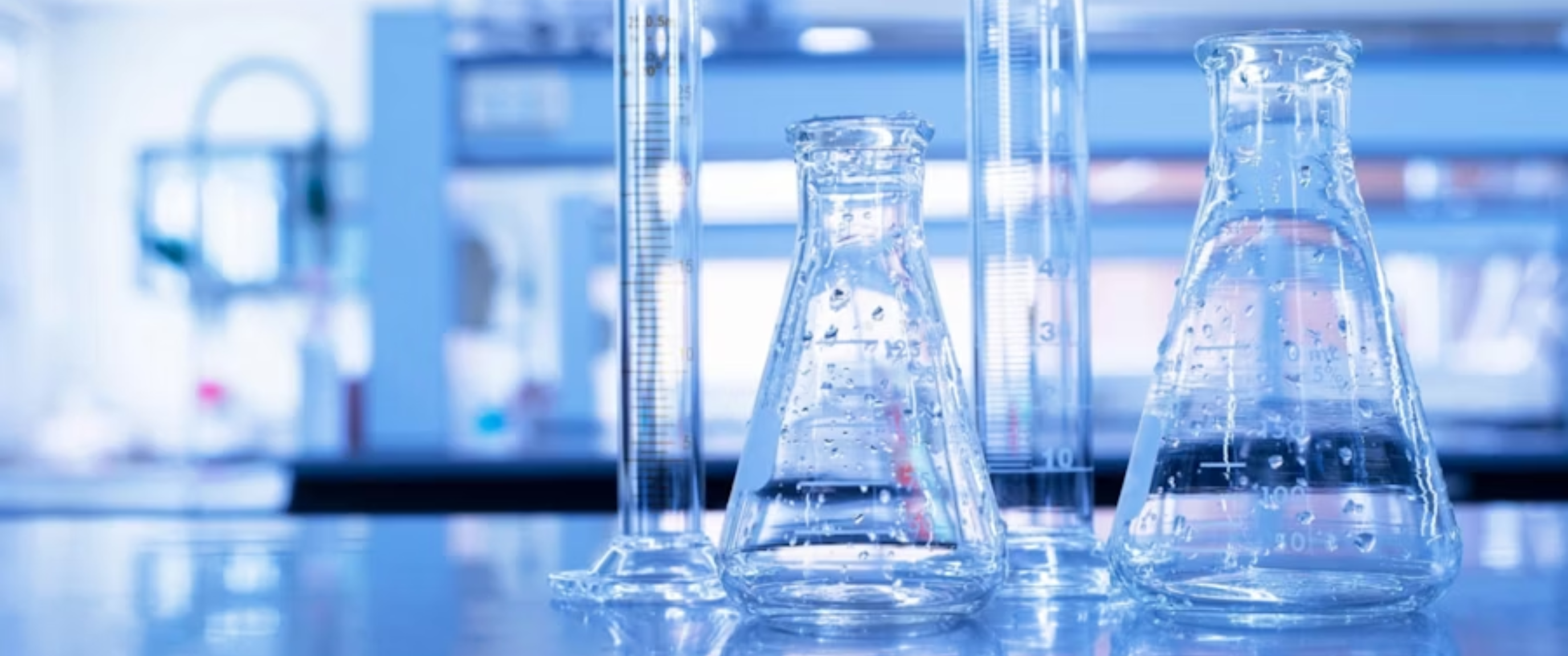 Laboratory glassware including flasks and measuring cylinders.