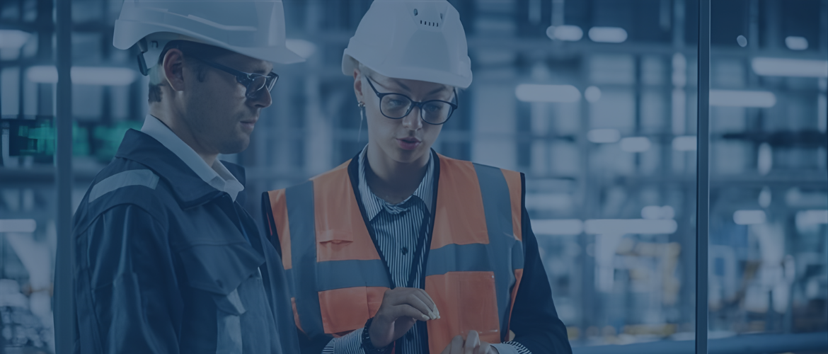 Engineers in safety gear reviewing data in a factory.
