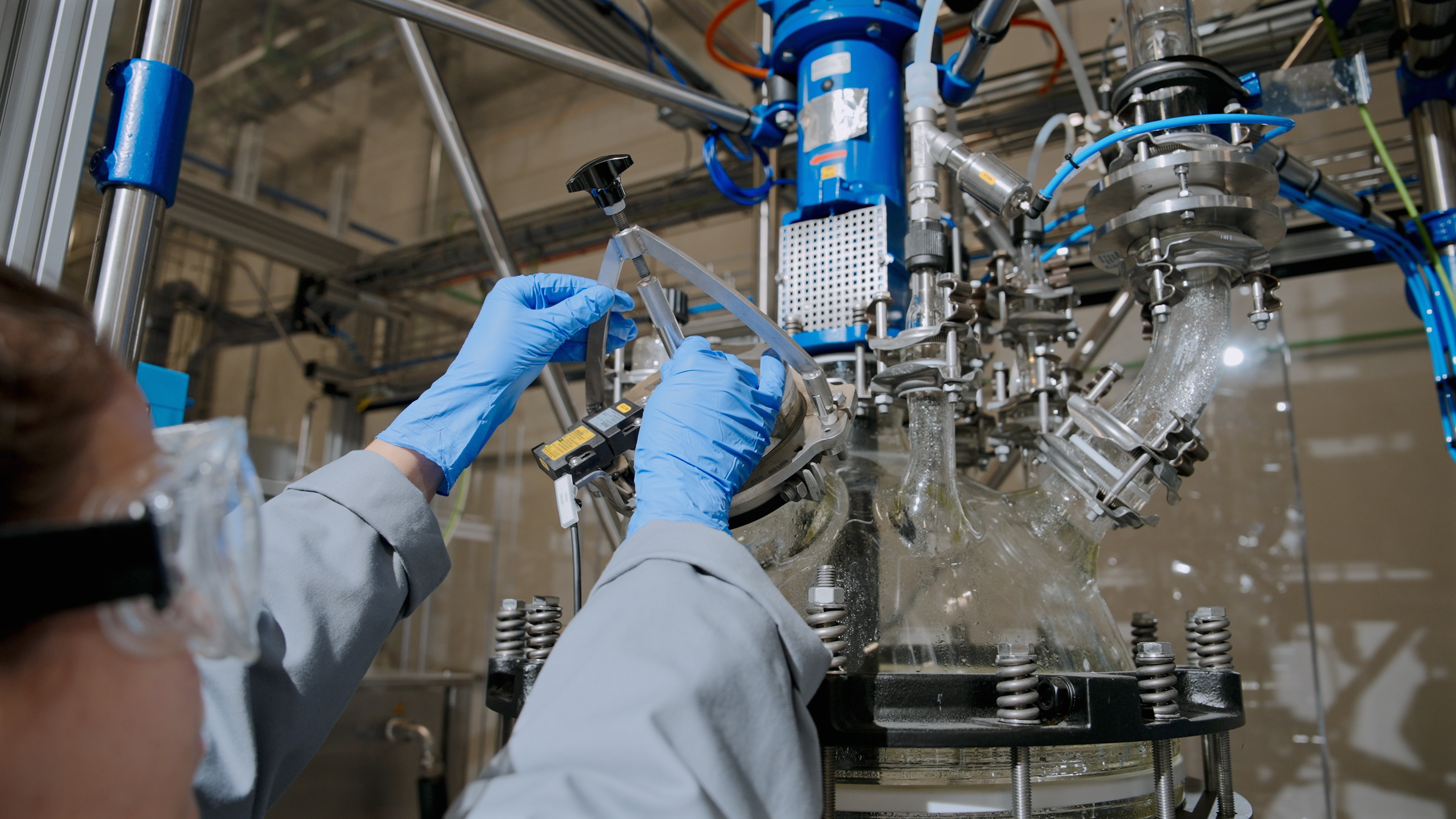 Technician working on industrial equipment with pipes and valves.