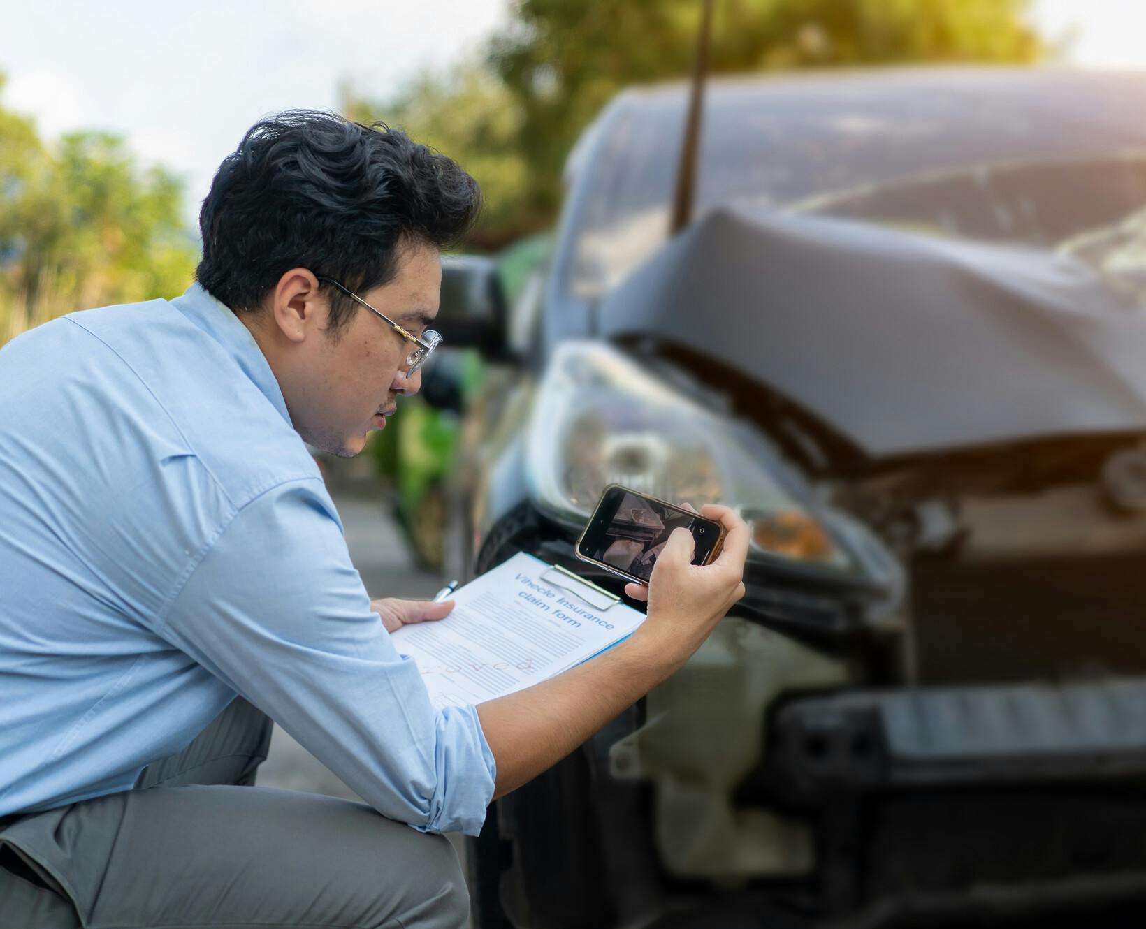 A man taking pictures of damage to his car