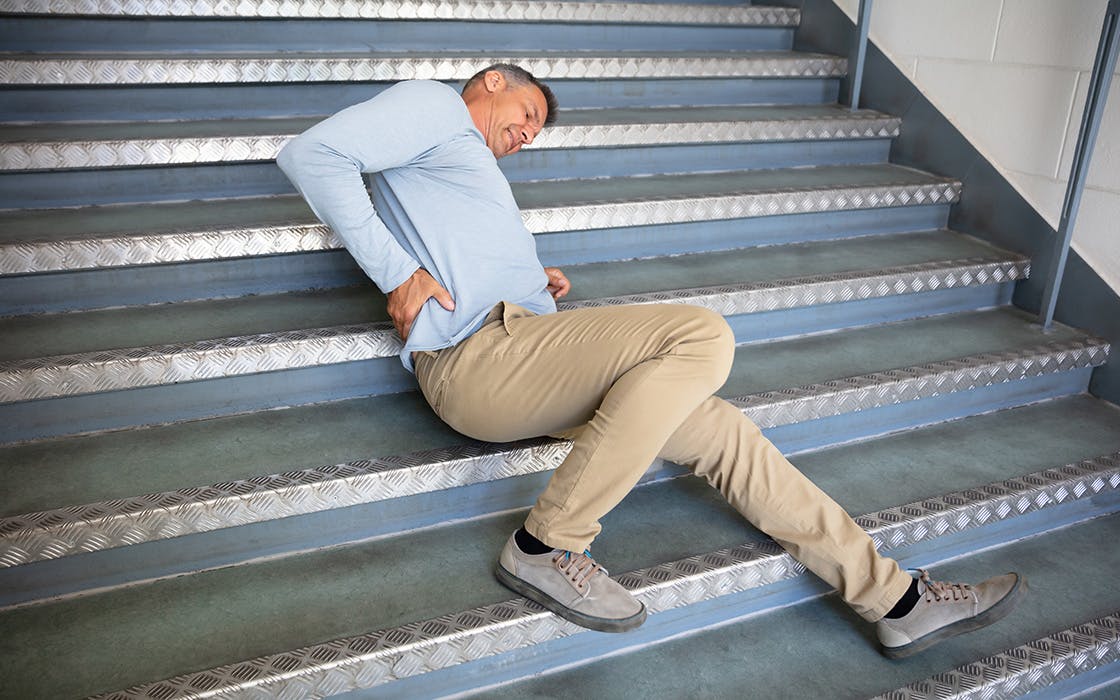 Man holding back on staircase