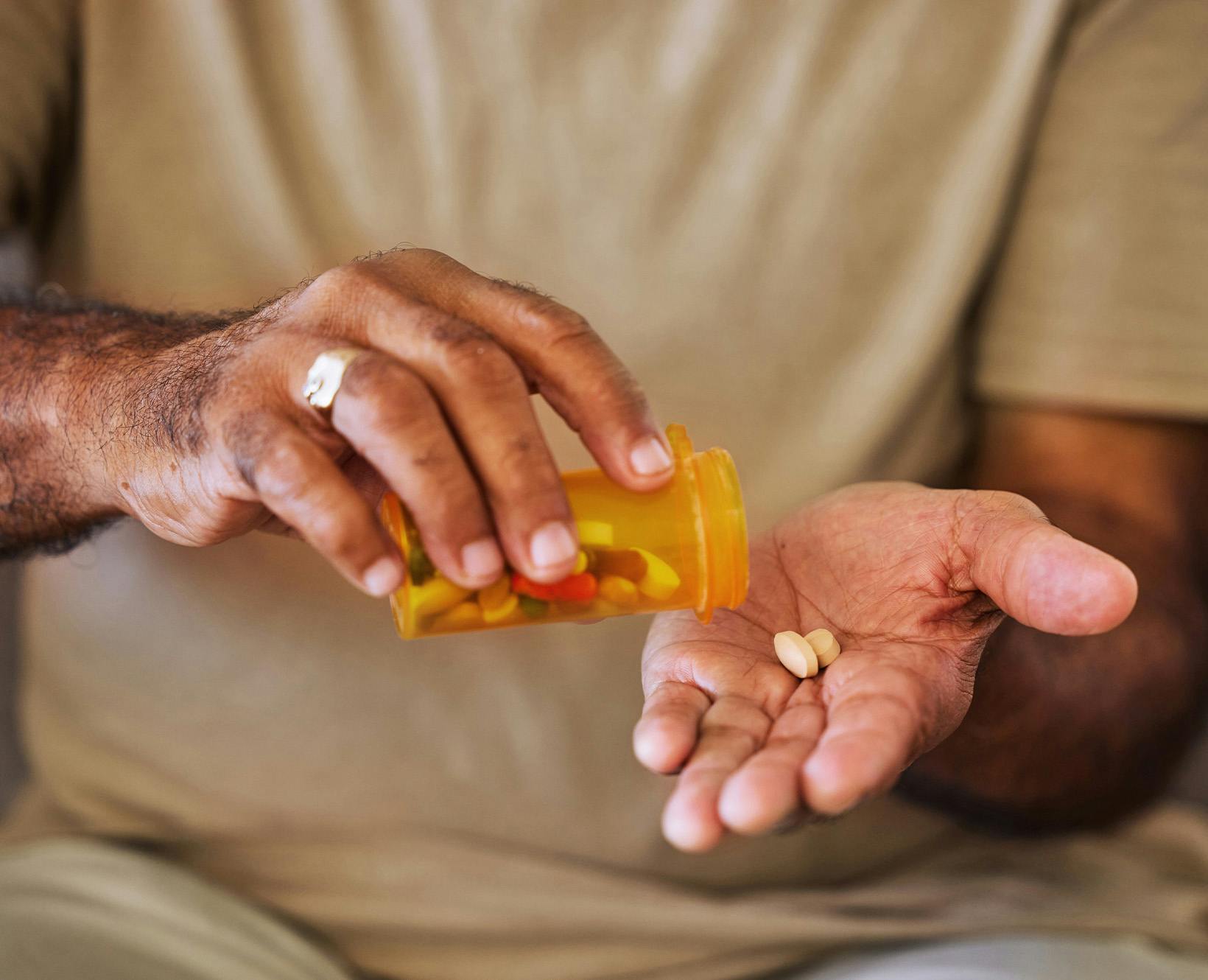 Man pouring pills out of bottle