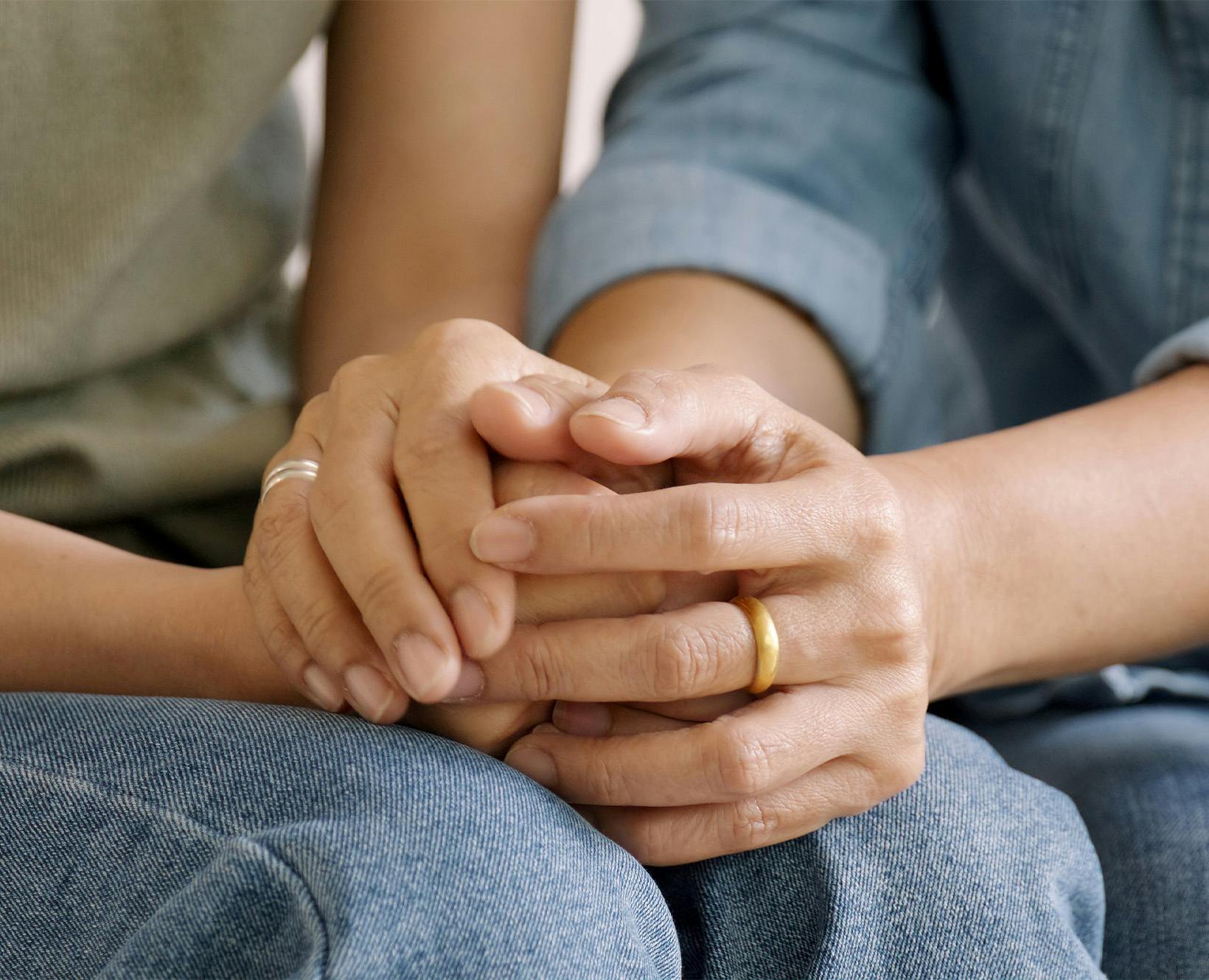 people holding hands grieving