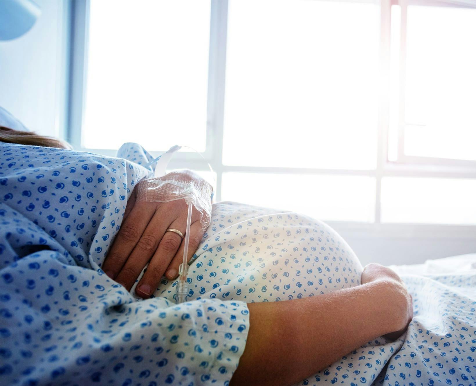 A pregnant woman laying in hospital bed