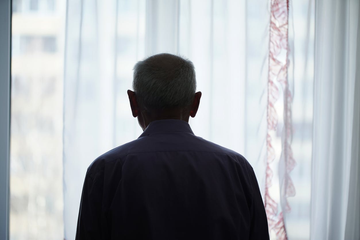 The back of an older man looking outside