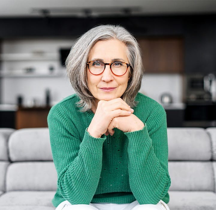 older woman sitting on a couch with her chin resting on her hands