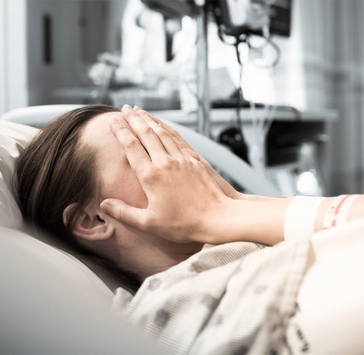woman in a hospital bed, coverign her face