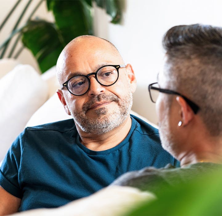 two older men talking to each other on a couch
