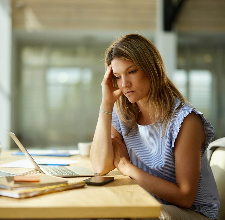 woman looking upset, sitting at a desk