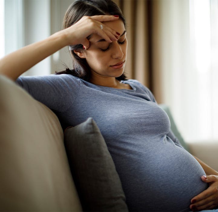 pregnant woman looking sad on a couch