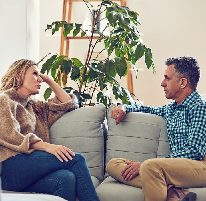 man and a woman talking to each other on a couch