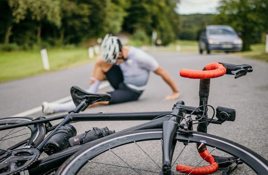 man in pain, laying on the ground next to a bike