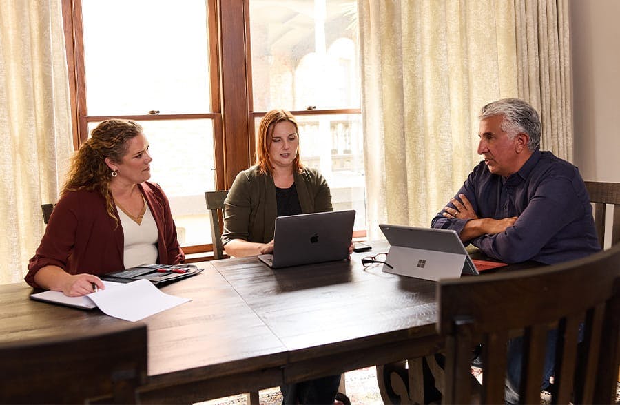 three people sitting around a table working on laptops