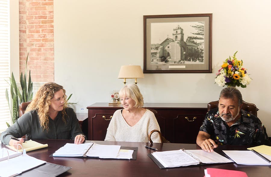 three people working on paperwork at a table