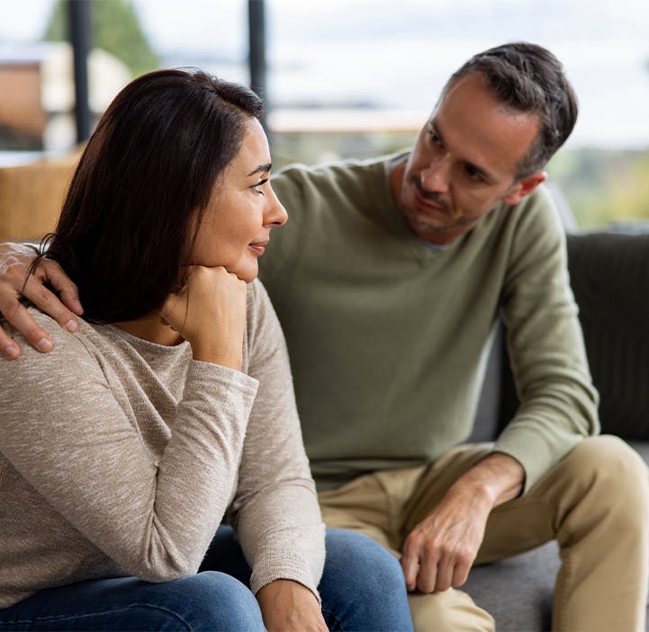 man and woman talking on a couch