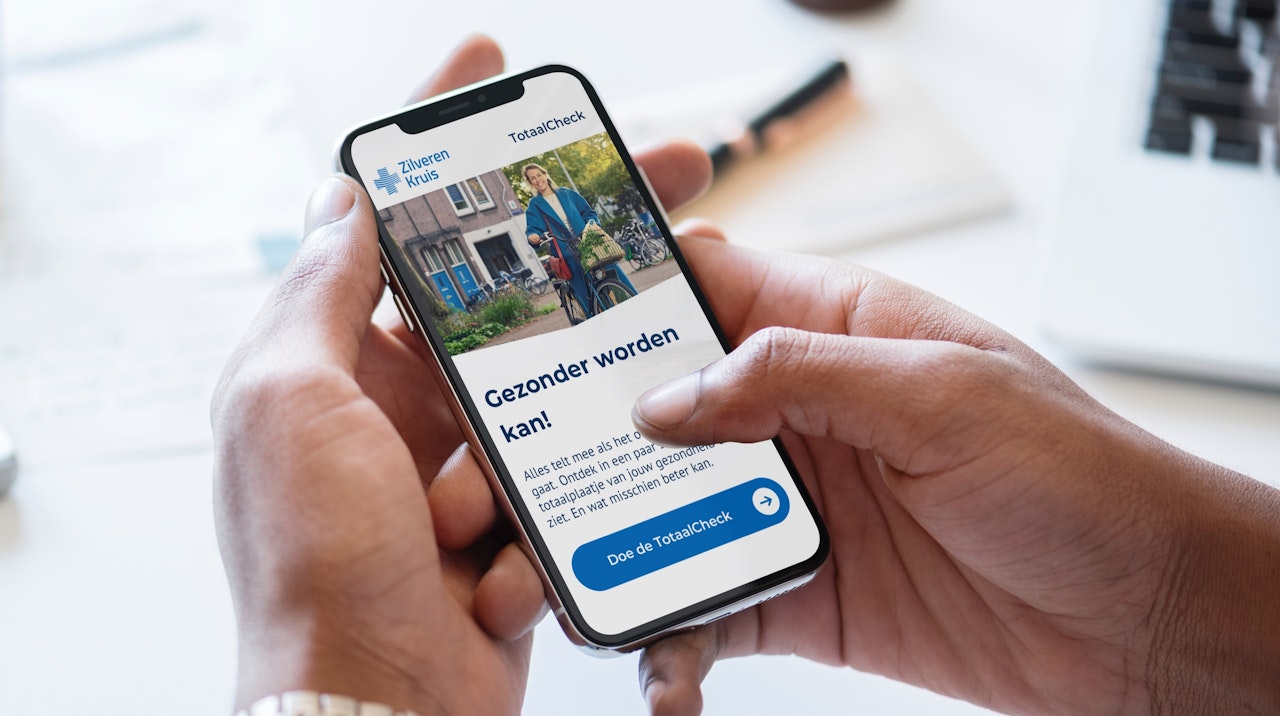 Handen die een smartphone vasthouden met een schermafbeelding van de Zilveren Kruis TotaalCheck.