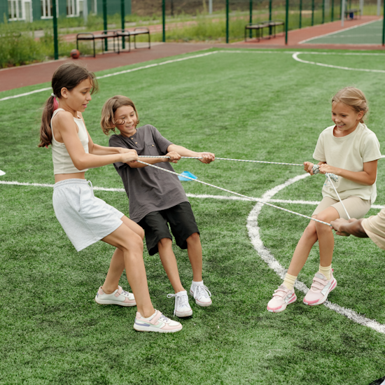 Kinderen spelen met een touw op een grasveld.