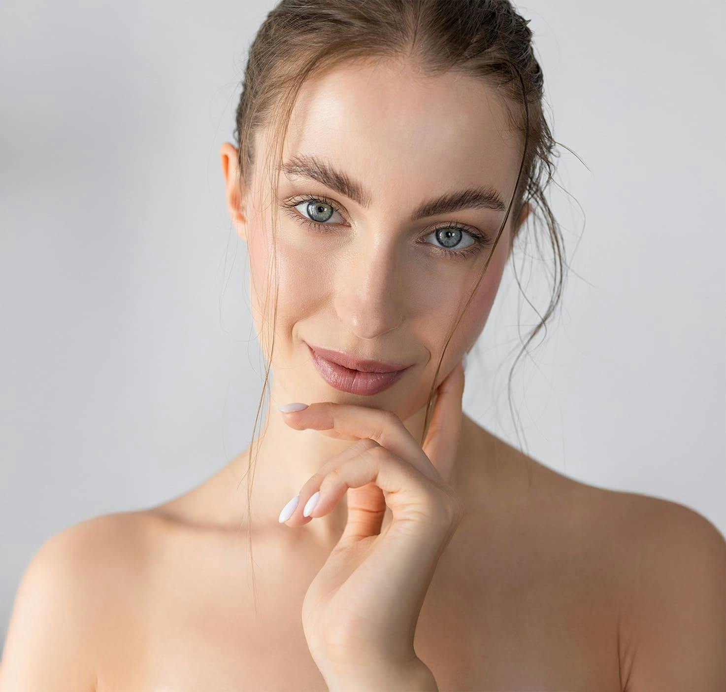 woman with head tilted and touching cheek looking forward